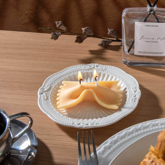 Realistic Farfalle Food Pasta Candle is lit up and sitting on the plate as unique candle gifts. 