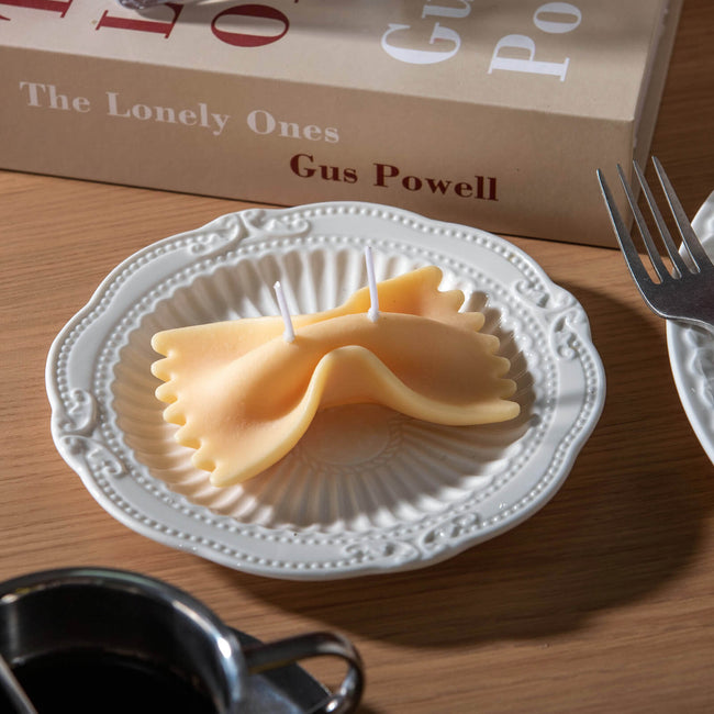 Realistic Farfalle Food Pasta Candle  sitting on the plate on the table. 
