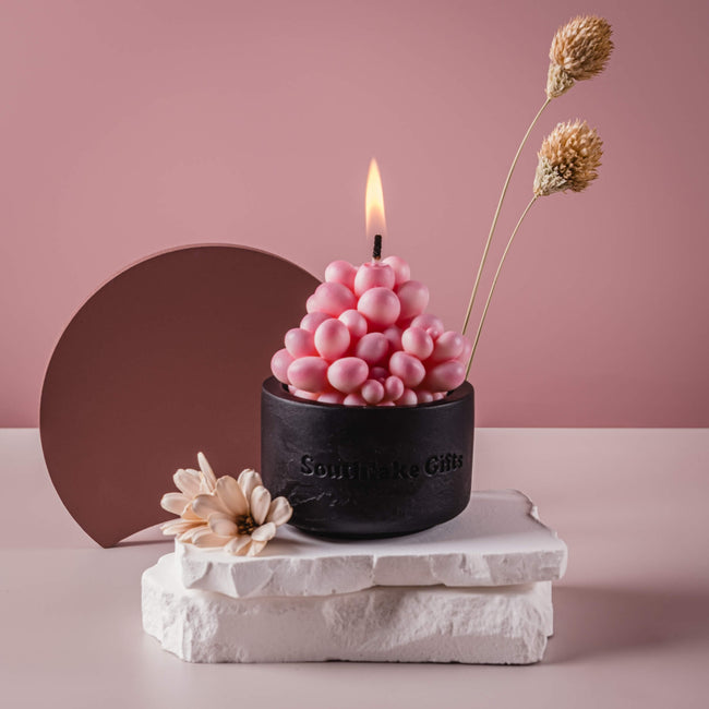 Pink Moonstone Succulent Candle is lit on fire in a pink background as home decor plant candle. 