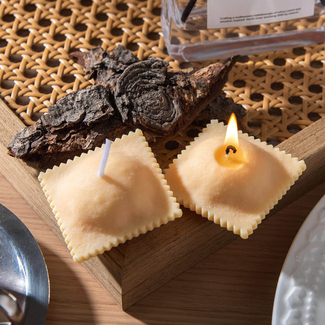 Realistic Ravioli Food Pasta Candle set comes in two Ravioli candles, and one of them is lit up and sitting on the table as unique candle decoration . 