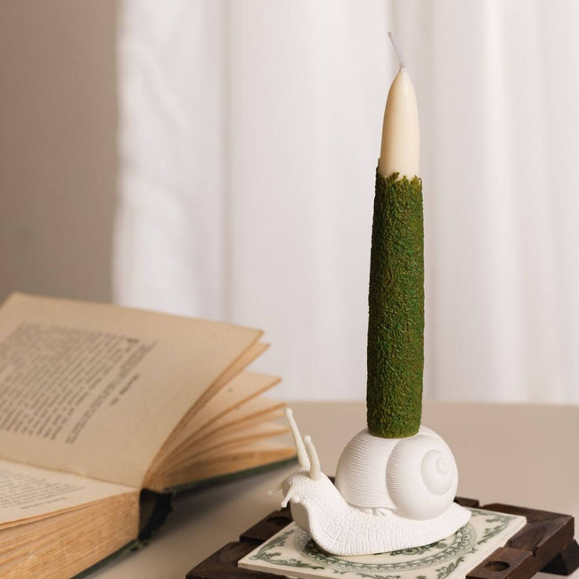 The Moss Taper Candle and Snail Candle Holder Set: A beautifully-crafted set that adds an elegant touch to any home decor or table setting. A taper candle with natural moss texture and a unique snail-shaped holder, handcrafted by Southlake Gifts Canada